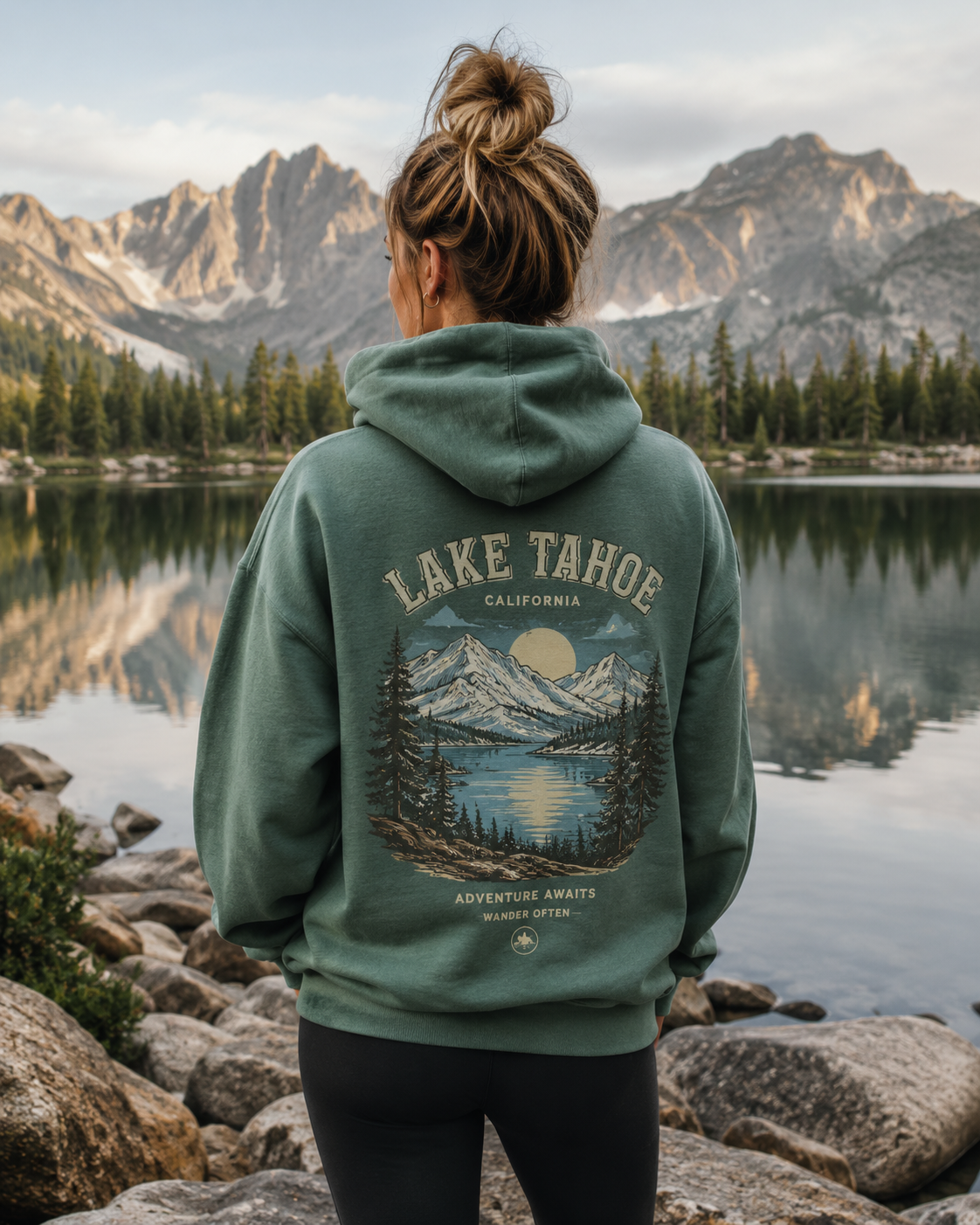 Person in Lake Tahoe hoodie by mountain lake